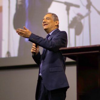 Pastor Mario Vega predicando desde el púlpito durante un servicio